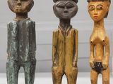 trois figurines en bois représentant des hommes debout les uns à côté des autres sur une table