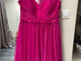 a pink dress hanging on a hanger in a room