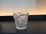 a glass of water sitting on a shelf next to a bottle of water