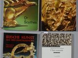 quatre livres posés sur une table, accompagnés d'une brochure dorée et d'autres objets