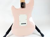 an electric guitar with a pink body sitting on a stand