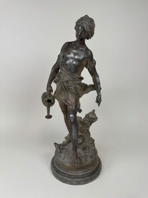 une statue antique en bronze représentant une femme tenant une cruche