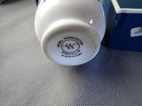 a white cup sitting on a table next to a blue box