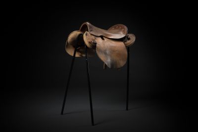 a horse saddle on a stand against a black background