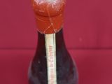 a small bottle of syrup on a red surface