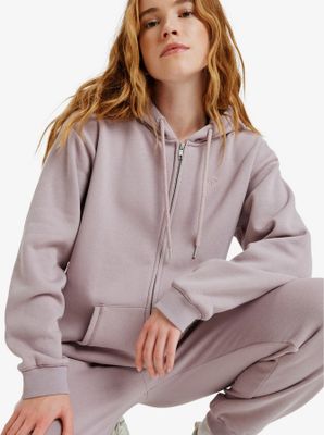 une femme vêtue d'un sweat à capuche violet et d'un pantalon de survêtement, accroupie