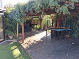 a wooden deck with a table and chairs under a pergol