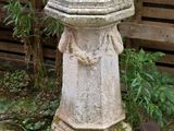 a stone statue sitting in the middle of a garden