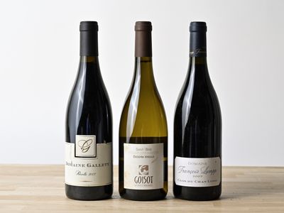 trois bouteilles de vin sont alignées sur une table en bois