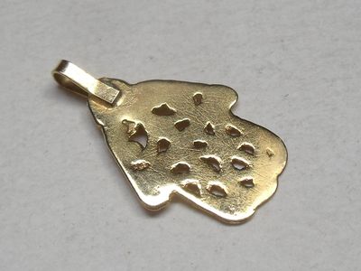 a close up of a gold pendant on a white surface