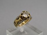 une photo d'une bague en or et diamants posée sur un socle transparent