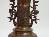 a bronze vase with a bird and flower decoration on it