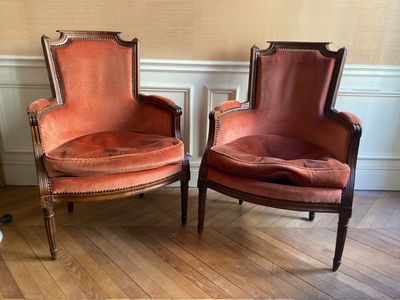 une paire de fauteuils en velours rouge dans un coin de la pièce