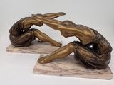 bronze statue of two women sitting on a marble base