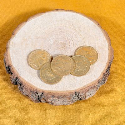 three coins sitting on a piece of wood on a yellow background