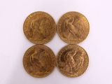 four gold coins sitting on top of each other on a white surface