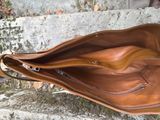 someone is holding a brown leather bag on a stone ledge