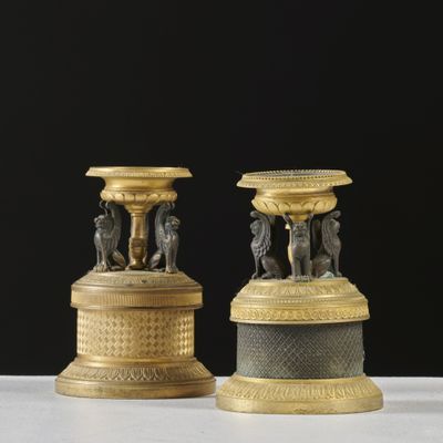 paire de bougeoirs anciens en laiton ornés de figurines sur des socles
