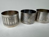 three silver napkins with designs on them sitting on a table
