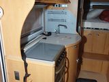 an image of a kitchen in a camper with a sink and stove