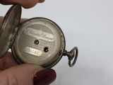a person holding a silver pocket watch in their hand