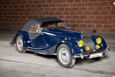 a blue car parked in front of a brick wall