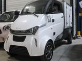 une petite voiture blanche garée dans un garage à côté d'une voiture rose