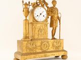 a gold clock with a statue on top of it