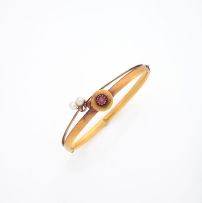 un gros plan sur un bracelet orné d'une perle et d'une pierre rouge