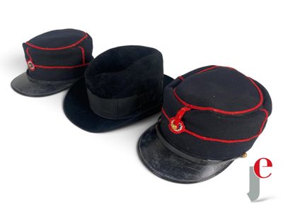 two black hats with red trims are sitting on a white surface