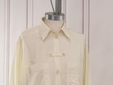 beige shirt on a mannequin stand against a striped wall