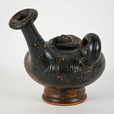 a black vase with a face on it on a stand