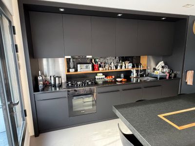 une cuisine avec un plan de travail noir et des placards noirs