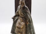 statue en bronze représentant une femme vêtue d'un manteau et d'une robe, tenant un livre