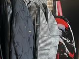 several jackets hanging on a rack in front of a brick wall