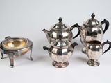three silver teapots and a silver bowl on a table