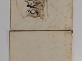two old books with drawings on them sitting on a table