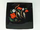 une assiette noire décorée de fleurs et d'oiseaux