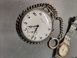 a silver pocket watch and a silver watch on a table
