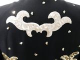 the back of a black jacket with gold sequins on it