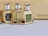 three small bottles of perfume sitting in front of a box