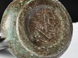 a close up of a green vase on a white surface