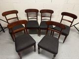 six chaises et un tabouret sont disposés en cercle dans une pièce