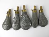 five antique silver and gold perfume bottles lined up on a white surface