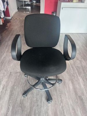 une chaise de bureau noire posée sur un parquet