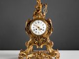 une horloge dorée posée sur une table blanche, sur fond noir
