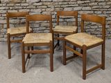 three wooden chairs sitting next to each other in front of a stone wall