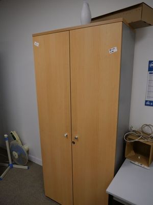 une armoire en bois placée dans un coin de la pièce, à côté d'un bureau
