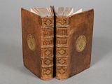 two old books sitting on top of each other on a table