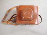 a brown leather camera case with a camera on it